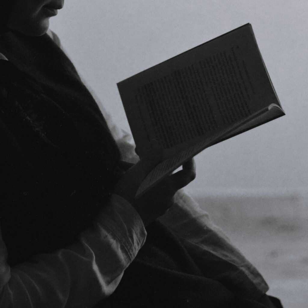 Silhouette of a woman reading a book, creating a serene and thoughtful atmosphere.