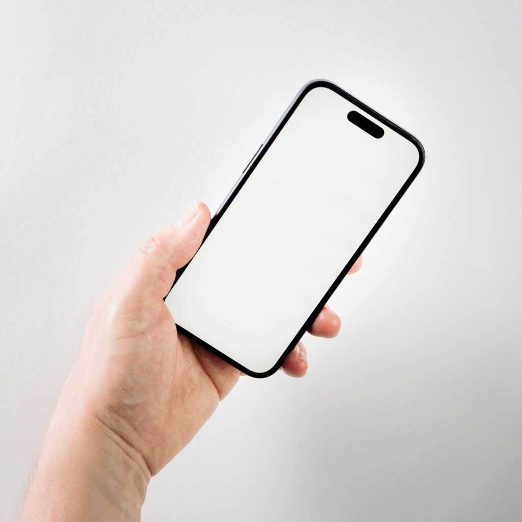 A hand holding a smartphone with a blank screen, ideal for app mockups and presentations.
