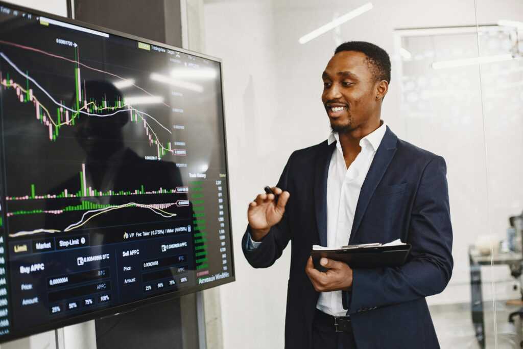 Professional man presenting financial data on a digital screen in modern office.